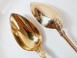 two gold spoons on a white plate on a red and white plate