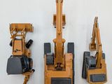 three toy construction vehicles that are on a white surface