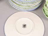 several plates and bowls are stacked on a table with a vase
