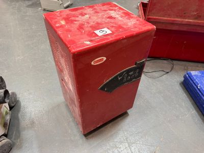 un petit réfrigérateur rouge posé à même le sol dans une pièce