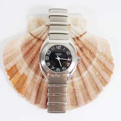 a watch sitting on top of a seashell on a white surface