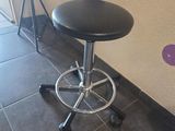 un tabouret noir posé devant un mur à pois