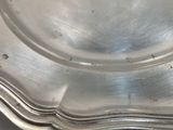 silver plate with scalloped edges on a black table