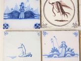 four blue and white tiles with birds and people on them