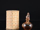 a small bottle of perfume sitting next to a box on a table