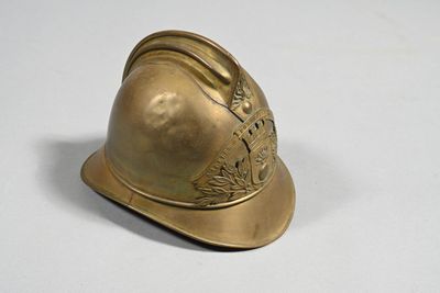 un casque de pompier doré posé sur une surface blanche