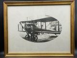 une vieille photo d'un homme debout à côté d'un petit avion
