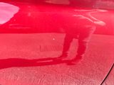 a red car with a person standing on the side of it