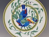 une assiette sur laquelle est peint un oiseau, posée sur un socle