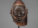 a wooden mask on a stand with a gray background