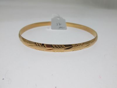 gros plan d'un bracelet en or sur une surface blanche