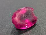pink diamond on a black surface with water droplets on it