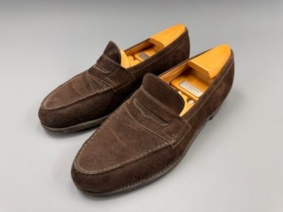 une paire de chaussures en daim marron posées sur une surface blanche