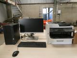deux ordinateurs et une imprimante posés sur un bureau dans un entrepôt