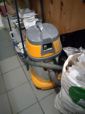 un aspirateur posé par terre à côté d'un sac poubelle