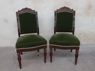 pair of green velveted chairs with wooden legs and a green upholstered seat