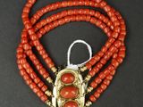 un gros plan sur un collier de perles rouges muni d'un fermoir doré