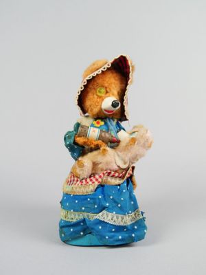 figurine représentant un ours en peluche vêtu d'une robe bleue et d'un bonnet, tenant un autre ours en peluche