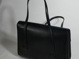 black leather handbag on a white surface with a white background