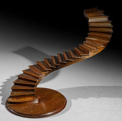 sculpture of a spiral staircase made of books on a wooden base