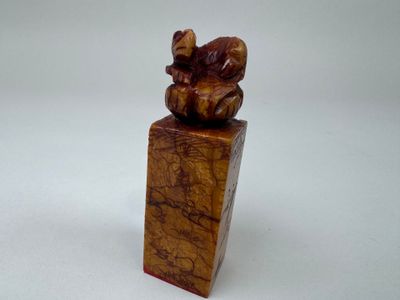 sculpture en bois représentant un ours posé sur un bloc, sur une surface blanche
