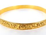 gros plan d'un bracelet en or sur une surface blanche