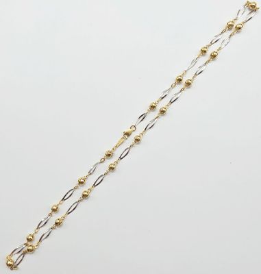 un gros plan d'un collier en or et en argent posé sur une surface blanche