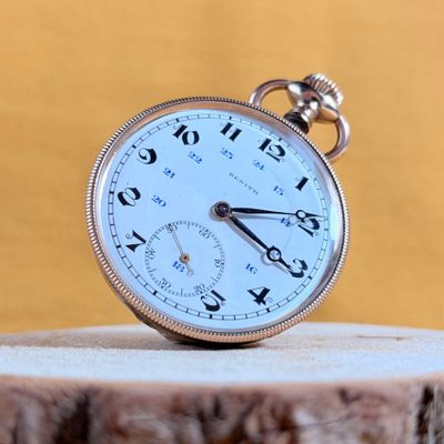 a pocket watch sitting on top of a piece of wood