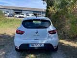 the rear end of a white car parked on a dirt road