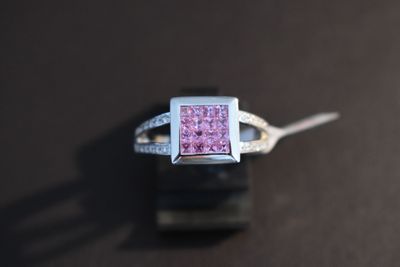 une bague en diamant rose posée sur une table noire