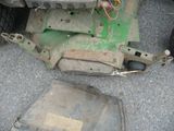 a green lawn mower sitting on the ground next to a car