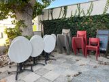 many chairs and tables that are outside by a tree