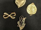 three gold brooches and a heart shaped brooch