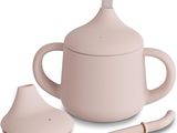 une théière rose avec une cuillère à côté, sur fond blanc
