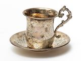 an antique silver cup and saucer on a saucer