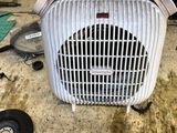 un ventilateur posé par terre à côté d'une table