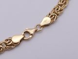 a close up of a gold chain bracelet on a white surface
