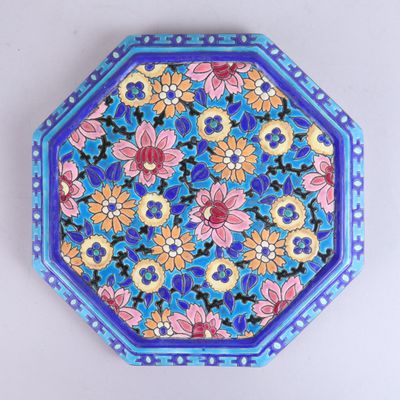 une image représentant une assiette décorative ornée de fleurs sur fond bleu