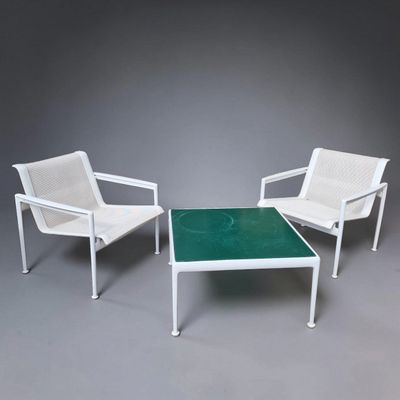 two white chairs and a table with a green top on a grey background