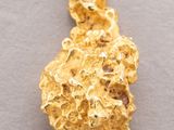 a close up of a gold nugget pendant on a gray surface
