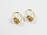une paire de boucles d'oreilles en or sur une surface blanche