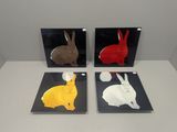 three different colored rabbits are displayed on black and white plates