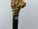 a close up of a golden dog head on a black cane