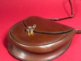 brown leather purse on a red surface with a brown strap