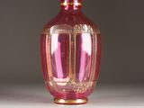 a pink glass vase with a gold rim on a table