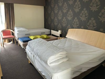 des lits dans une chambre d'hôtel avec un mur tapissé et une fenêtre