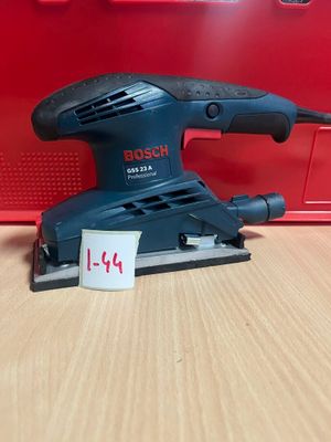 La ponceuse orbitale Bosch est posée sur une table, à côté d'une boîte rouge.
