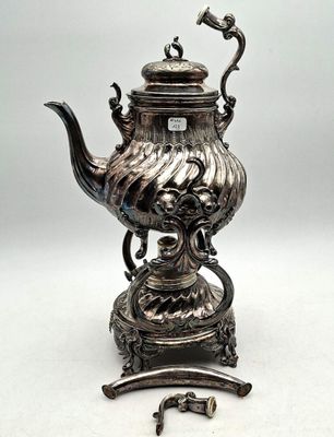a silver tea pot on a stand next to a key