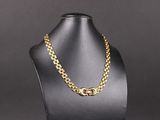 un collier à chaîne en or sur un mannequin, sur fond noir
