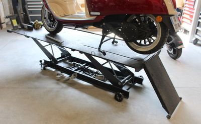 une moto rouge sur un pont élévateur dans un garage